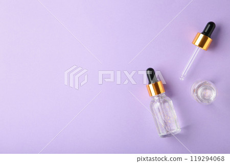 A glass bottles with a pipette with oil, serum on purple background with copy space. Flatlay 119294068
