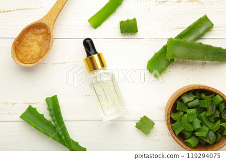 Aloe vera gel on wooden spoon with aloe vera and oil bottle on white background. Vertical photo 119294075