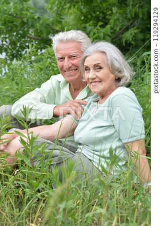Portrait of senior couple sitting on the grass in the park 119294129