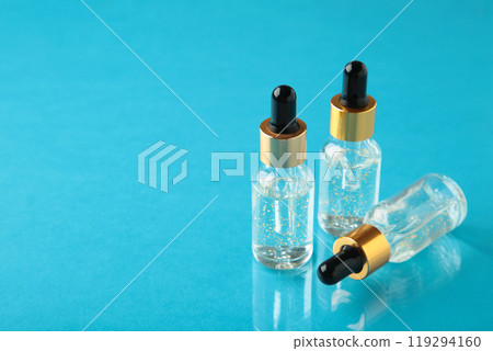A glass bottles with a pipette with oil, serum on blue background with copy space. Flatlay A glass bottles with a pipette with oil, serum on blue background with copy space. Flatlay 119294160