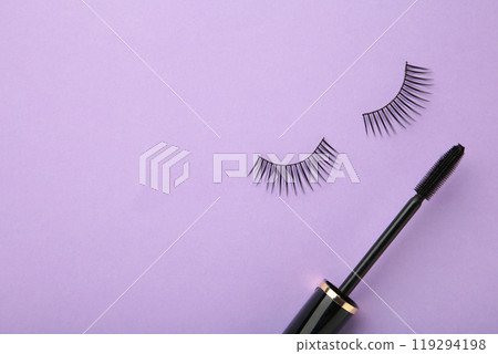 Black eyelashes and mascara on purple background with copy space 119294198