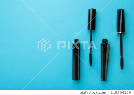 Black mascara wand and tube on blue background with copy space Black mascara wand and tube on blue background with copy space 119294199