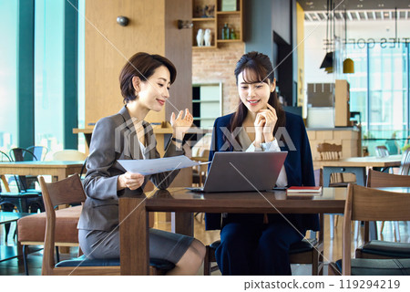 Two businesswomen having a meeting while using a computer in a cafe (casual) 119294219