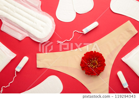 Women's panties with menstrual pads and tampons on red background. Top view. Concept of critical days, menstruation, feminine hygiene. A rose flower lies on a menstrual pad. Women's panties with menstrual pads and tampons on red background. Top view. Concept of critical days, menstruation, feminine hygiene. A rose flower lies on a menstrual pad. 119294343