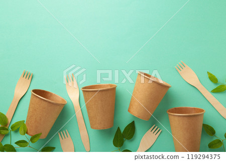 Eco friendly disposable glasses and fork with green leaves on mint background. Zero waste, eco friendly, plastic free background. Eco friendly disposable glasses and fork with green leaves on mint background. Zero waste, eco friendly, plastic free background. 119294375