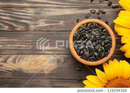 Sunflower with seeds in bowl on brown wooden background 119294388