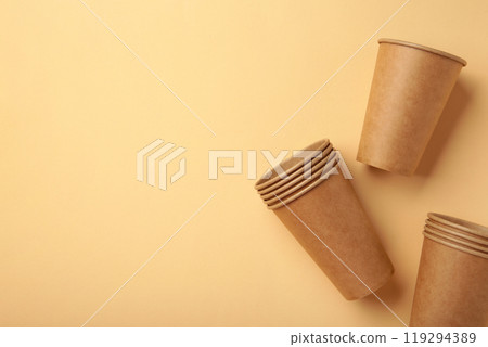 Disposable paper cups on beige background with copy space. Coffee concept. 119294389