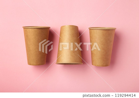 Disposable paper cups on pink background. Coffee concept. Disposable paper cups on pink background. Coffee concept. 119294414