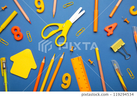 Yellow and orange school supplies on blue background with copy space. Back to school concept. Yellow and orange school supplies on blue background with copy space. Back to school concept. 119294534