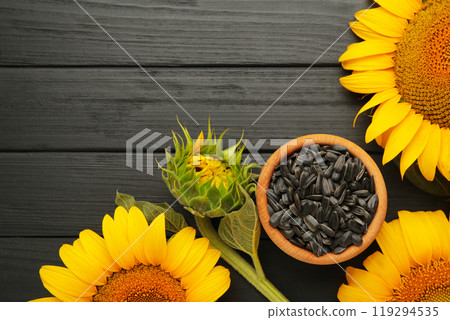 Sunflower seeds and bottle of oil on black wooden table. 119294535