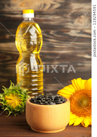 Sunflower seeds and bottle of oil on old wooden table. Sunflower seeds and bottle of oil on old wooden table. 119294591