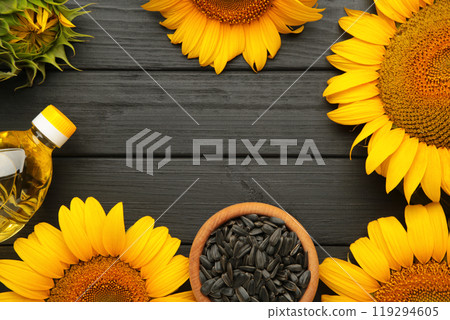 Sunflower seeds and bottle of oil on black wooden table. 119294605