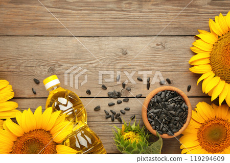 Sunflower oil, seed and sunflower on grey wooden background 119294609