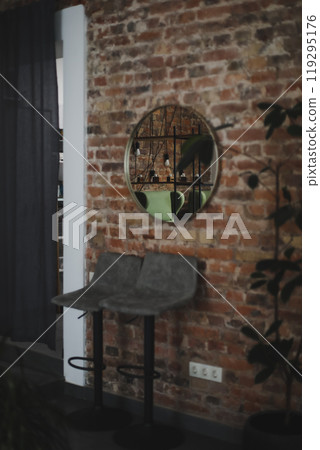 trendy loft interior with cozy armchairs next to a brick wall with round mirror. Loft interior style decoration. 119295176