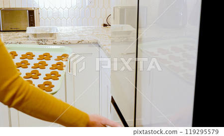 After cutting out adorable gingerbread shapes, the next step is placing the tray with cookies in the fridge for a delightful chill, enhancing their holiday flavor. 119295579