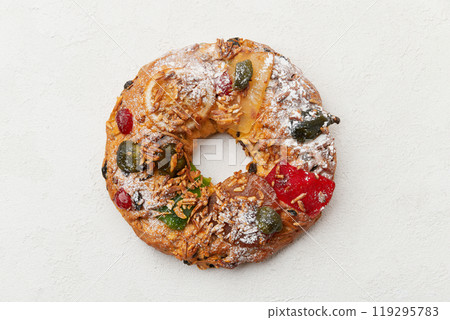 A top down view of a festive wreath shaped cake decorated with candied fruit and nuts on a white plate A top down view of a festive wreath shaped cake decorated with candied fruit and nuts on a white plate 119295783
