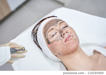 Woman undergoing laser facial treatment with protective headband in modern 119295909
