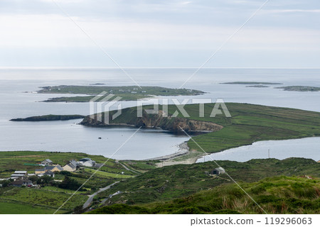 The coastal landscape of Clifden from Sky Road shows green fields, cliff edges, calm Atlantic waters 119296063