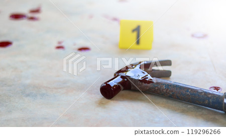 A bloodstained steel hammer lying on a concrete floor, with a blurred yellow marker number 1 and scattered blood drops, symbolizing a violent crime scene under investigation. A bloodstained steel hammer lying on a concrete floor, with a blurred yellow marker number 1 and scattered blood drops, symbolizing a violent crime scene under investigation. 119296266