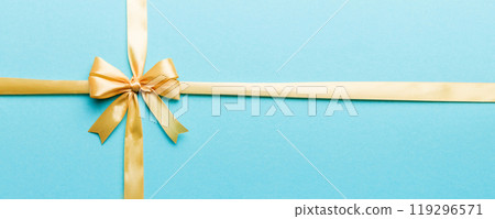Top view of gold ribbon rolled and yellow bow isolated on colored background. Flat lay with copy space 119296571