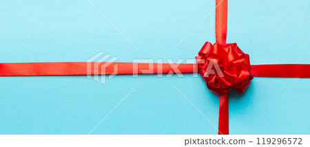 Top view of Red ribbon rolled and red bow isolated on colored background. Flat lay with copy space 119296572
