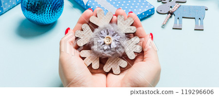 Top view of snowflake in female hands on blue background. Christmas decorations. New Year holiday concept Top view of snowflake in female hands on blue background. Christmas decorations. New Year holiday concept 119296606
