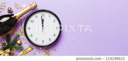 New year celebration concept with a bottle of champagne and two glasses toasting. Christmas gift box, alarm clock and fir tree branch on colored table. Top view Copy space New year celebration concept with a bottle of champagne and two glasses toasting. Christmas gift box, alarm clock and fir tree branch on colored table. Top view Copy space 119296622