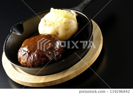 Hamburg steak and buttered potatoes photographed against a black background Hamburg steak and buttered potatoes photographed against a black background 119296842