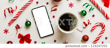 top view of smart phone with hot cup of coffee. Christmas decoration on colored background 119297205