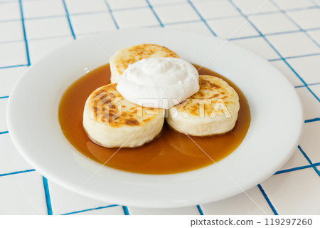 A pristine white plate elegantly topped with a delicious stack of three fluffy pancakes adorned with a generous amount of whipped cream A pristine white plate elegantly topped with a delicious stack of three fluffy pancakes adorned with a generous amount of whipped cream 119297260