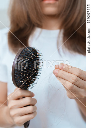 Hair loss problem, Balding , Beauty treatments and health care concepts asian woman holding holding comb with hair loss, young female hold hairbrush and brushing with fall hair from scalp 119297335