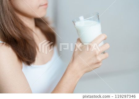 Milk drink and Daily Routine concept. Young woman Drinking milk with high calcium and nutrition at home, woman holding soy milk on glass with protein. Healthy, wellness and happy lifestyle 119297346