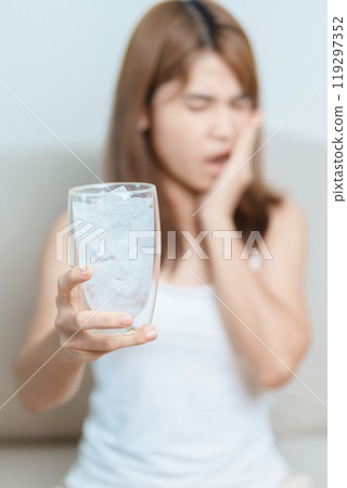 Teeth Sensitive to Cold concept. woman hold Ice Water glass and having toothache and pain after eat. Tooth Decay or Gum Disease, Grinding Teeth and Stress, Exposed Nerve Roots, Crack and Receding Gums Teeth Sensitive to Cold concept. woman hold Ice Water glass and having toothache and pain after eat. Tooth Decay or Gum Disease, Grinding Teeth and Stress, Exposed Nerve Roots, Crack and Receding Gums 119297352