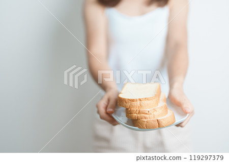 Bread eating and Daily Routine concept. Young woman Hand holding sliced whole grain bread in the morning at home Bread eating and Daily Routine concept. Young woman Hand holding sliced whole grain bread in the morning at home 119297379