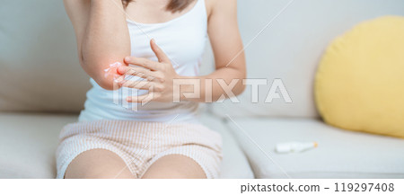 Arthritis and Muscle Pain Relief Cream concept. Woman having elbow ache at home, muscle pain due to lateral epicondylitis or tennis elbow. injury, Health and medical concept Arthritis and Muscle Pain Relief Cream concept. Woman having elbow ache at home, muscle pain due to lateral epicondylitis or tennis elbow. injury, Health and medical concept 119297408