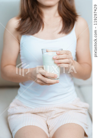 Milk drink and Daily Routine concept. Young woman Drinking milk with high calcium and nutrition at home, woman holding soy milk on glass with protein. Healthy, wellness and happy lifestyle 119297429