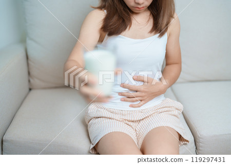 Lactose intolerance and Milk allergy concept. woman hold Milk glass and having abdominal cramps and pain when drink Cow Milk. Symptom stomach ache, Dairy intolerant, Nausea, Bloating, Gas and Diarrhea 119297431