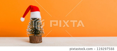 One small Christmas tree with santa hat on colored background. new year decoration with copy space 119297588