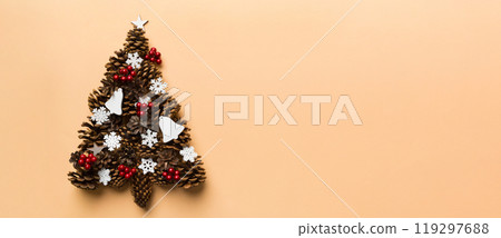 Christmas tree made from natural cones on colored background, view from above. New Year minimal concept with copy space Christmas tree made from natural cones on colored background, view from above. New Year minimal concept with copy space 119297688