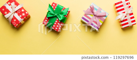 Holiday flat lay with gift boxes wrapped in colorful paper and tied decorated with confetti on colored background. Christmas, Birthday, Valentine and sale concept, top view 119297696