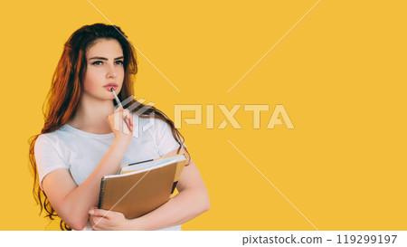 Pensive student. Smart contemplation. Serious puzzled girl with notepad pen thinking considering ideas isolated on yellow empty space background. 119299197