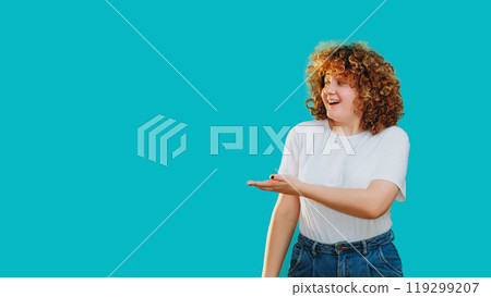 Joyful woman smiles points radiating positive energy enthusiasm isolated on blue empty space background. 119299207