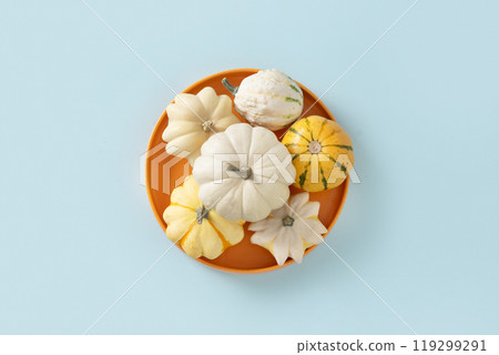 Autumn concept with small pumpkins in seasonal orange plate on blue background. View from above. Thanksgiving Day. Preparation to celebrate. Autumn concept with small pumpkins in seasonal orange plate on blue background. View from above. Thanksgiving Day. Preparation to celebrate. 119299291