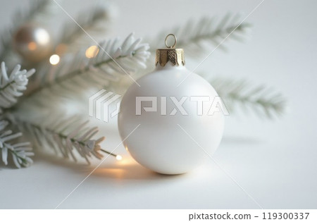 A beautiful white christmas ornament is gently resting next to a green christmas tree branch that is part of the festive decoration 119300337