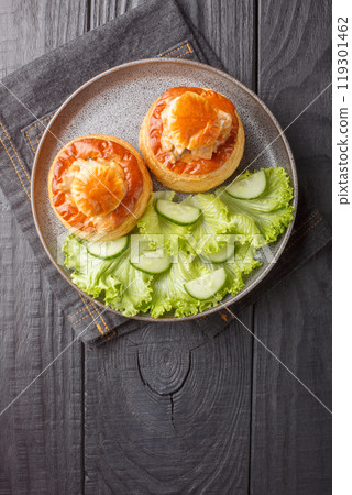 Puff pastry Bouchee or vol-au-vent with veal in spicy sauce served with lettuce and cucumber close-up in a plate. Vertical top view Puff pastry Bouchee or vol-au-vent with veal in spicy sauce served with lettuce and cucumber close-up in a plate. Vertical top view 119301462
