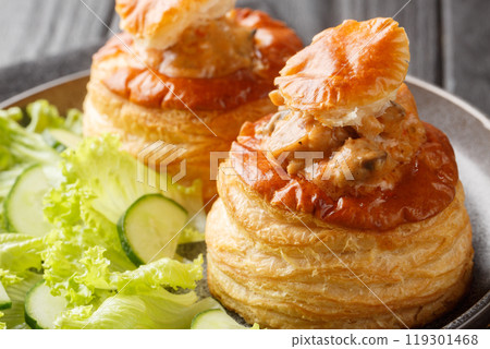Puff pastry Bouchee or vol-au-vent with veal in spicy sauce served with lettuce and cucumber close-up in a plate. Horizontal 119301468