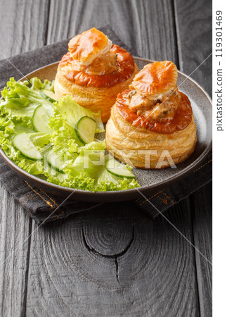 Bouchee a la reine or vol-au-vent with veal in spicy sauce served with lettuce and cucumber close-up in a plate. Vertical 119301469