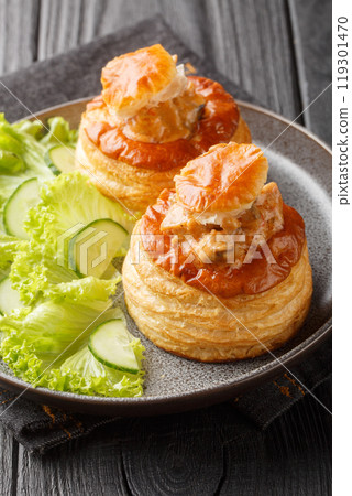 French bouchee puff pastry filling with veal in spicy sauce served with lettuce and cucumber close-up in a plate. Vertical 119301470