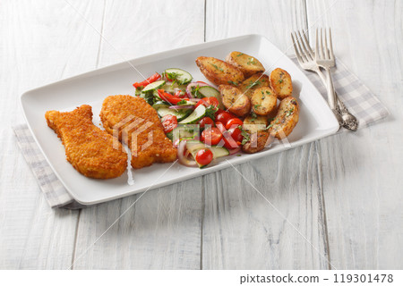 Crispy breaded white fish with fresh salad and country style fried potatoes close-up in a plate. Horizontal 119301478
