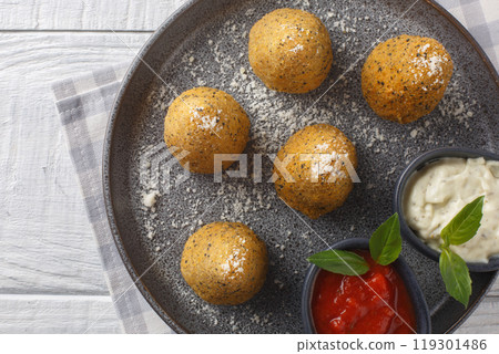 Homemade Fried Risotto Arancini stuffed with cheese served with two sauces close-up in a plate. Horizontal top view 119301486